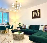 Wohnzimmer in einer 3-Zimmer-Wohnung mit einem auffälligen grünen Sofa und Marmorboden.
