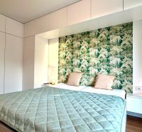 Schlafzimmer in einer 3-Zimmer-Wohnung mit Holzboden und grüner Tapete.