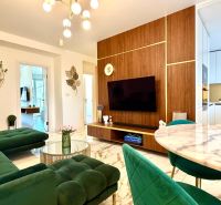 Wohnzimmer in einer 3-Zimmer-Wohnung mit Marmorboden und grünen Sofas.