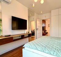 Schlafzimmer in einer 3-Zimmer-Wohnung mit Fernseher und Boden in Holzoptik.