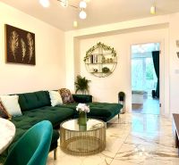 Innenraum einer 3-Zimmer-Wohnung mit Sofa, Glastisch und künstlerischen Dekorationen an der Wand.