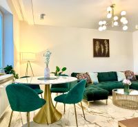 Wohnzimmer in einer 3-Zimmer-Wohnung, grünes Sofa, Marmortisch, auffällige Leuchte.