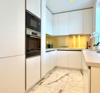 Weiße Küche in einer 3-Zimmer-Wohnung mit Marmorboden und eingebauten Geräten.
