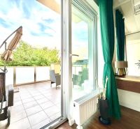 Innenraum einer 3-Zimmer-Wohnung mit Terrasse, Boden mit Holzdekor, grüne Vorhänge.