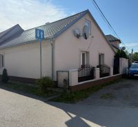Ein Einfamilienhaus in Záhorská Ves mit einer Satellitenschüssel und einem blauen Auto, das vor dem Haus geparkt ist.