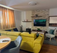 Wohnzimmer in einem Einfamilienhaus mit einem bequemen gelben Sofa und einem Boden in Holzoptik.