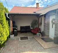 Einfamilienhaus in Záhorská Ves, Terrasse mit Sitzgelegenheit, grüne Thujen, weiße Eingangstür.