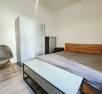 Schlafzimmer in einer 2-Zimmer-Wohnung mit Holzbett, Schrank und Stuhl.