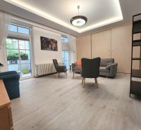Wohnzimmer in einer 2-Zimmer-Wohnung, Boden mit Holzdekor, Möbel, große Fenster.