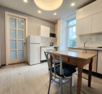 Küche in einer 2-Zimmer-Wohnung mit Holzboden, weißer Küchenzeile und Fenster.