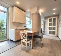 Küche in einer 2-Zimmer-Wohnung mit Holztisch und Boden in Holzoptik.