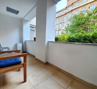 Balkon einer 2-Zimmer-Wohnung mit Blick auf Grünflächen und ein Gebäude, Sitzgelegenheit mit Stühlen.