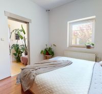 Schlafzimmer mit Holzboden, großem Bett und Zimmerpflanzen in einem Einfamilienhaus.