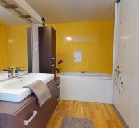 Badezimmer mit Holzboden, gelben Fliesen und Waschbecken in einem Einfamilienhaus.