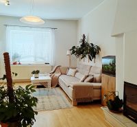 Wohnzimmer mit Sofa, Kamin, Zimmerpflanzen und Aquarium, Boden mit Holzdekor.