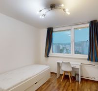 Ein Zimmer in einer 3-Zimmer-Wohnung mit einem Bett, einem Schreibtisch und einem Boden mit Holzdekor.