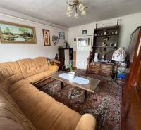 Wohnzimmer in einem Einfamilienhaus mit braunem Sofa, Teppich und dekorativen Bildern an den Wänden.