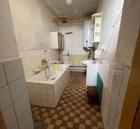 Badezimmer mit Badewanne in einem Einfamilienhaus, gefliest mit Heizkörper und Gaskessel.