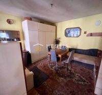 Wohnzimmer mit Teppichen, Holzelementen und einfacher Einrichtung in einem Einfamilienhaus.