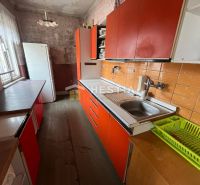 Eine Küche in einem Einfamilienhaus mit orangefarbenen Schränken und einem Boden in Holzoptik.