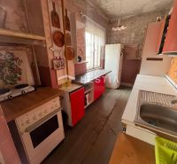 Eine Küche in einem Einfamilienhaus mit einem Boden in Holzoptik und Retro-Möbeln.