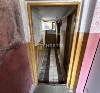 Ein enger Flur mit beschädigten Wänden und einem gefliesten Boden in einem Einfamilienhaus.