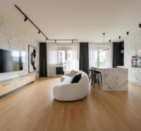 Wohnzimmer in einer 4-Zimmer-Wohnung mit Holzboden und Marmordekor an den Wänden.