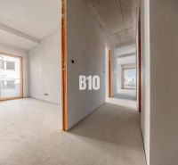 Flur in einer 3-Zimmer-Wohnung mit großen Fenstern und Betonboden.
