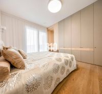 Schlafzimmer in einer 3-Zimmer-Wohnung mit Bett, Einbauschrank und Boden in Holzoptik.