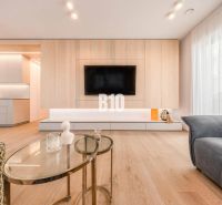 Wohnzimmer in einer 3-Zimmer-Wohnung mit Holzboden und einem Fernseher an der Wand.