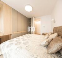 Schlafzimmer in einer 3-Zimmer-Wohnung mit Stauraum und einem Bett mit gemusterten Textilien.