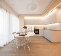 Küche in einer 3-Zimmer-Wohnung mit weißen Möbeln und einem Boden in Holzoptik.