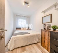 Schlafzimmer mit Bett, Kommode und Holzboden in einer 2-Zimmer-Wohnung.