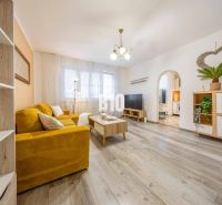 Wohnzimmer in einer Zweizimmerwohnung mit gelbem Sofa und Holzboden.