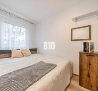 Schlafzimmer in einer 2-Zimmer-Wohnung mit Bett, Regalen und Boden mit Holzdekor.