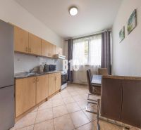Küche mit Holzschränken, Esstisch und großem Fenster, Büros.