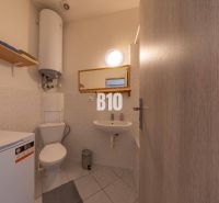 Badezimmer mit Waschmaschine, Waschbecken, Spiegel und Boiler im Büro.