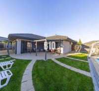 Ein Einfamilienhaus in Most pri Bratislave mit Terrasse, Pool und Liegestühlen im Garten.