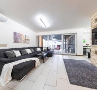 Wohnzimmer eines Einfamilienhauses mit Sofa, Kamin und Schiebetüren zur Terrasse.