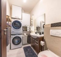 Badezimmer in einem Einfamilienhaus mit Waschmaschine, Trockner, Waschbecken und Stauraum.