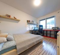 Schlafzimmer im Einfamilienhaus mit Schreibtisch, Regalen und Holzboden.