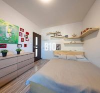 Schlafzimmer in einem Einfamilienhaus mit Bett, Regalen, Bildern und Boden mit Holzdekor.