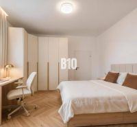 Schlafzimmer in einer 4-Zimmer-Wohnung mit Holzboden, Schreibtisch und Einbauschrank.