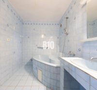 Ein Badezimmer mit hellblauen Fliesen, einer Badewanne und einem Waschbecken in einer 4-Zimmer-Wohnung.