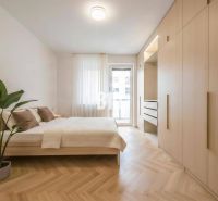 Schlafzimmer in einer 4-Zimmer-Wohnung mit einem großen Schrank und einem Boden in Holzoptik.