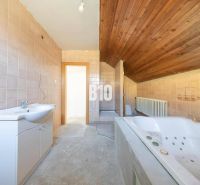 Badezimmer in einem Einfamilienhaus mit Badewanne, Fliesen und Holzdecke.