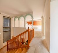 Innenraum eines Einfamilienhauses mit Holztreppe und Rundsäulen.