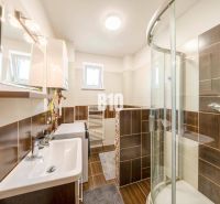 Badezimmer in einer 2-Zimmer-Wohnung mit dunklen Fliesen und Duschkabine.