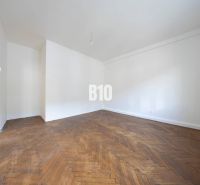 Ein geräumiges Zimmer mit weißen Wänden und einem Boden in Holzoptik in einer 3-Zimmer-Wohnung.