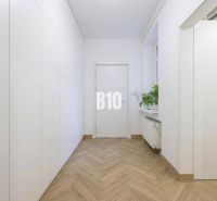 Ein gemütlicher Flur mit weißen Wänden, einem Boden in Holzoptik und einer Pflanze in einer 3-Zimmer-Wohnung.